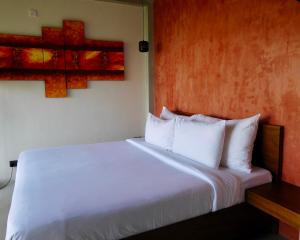 a bedroom with a white bed with a cross on the wall at GlenMyu Estate in Haputale