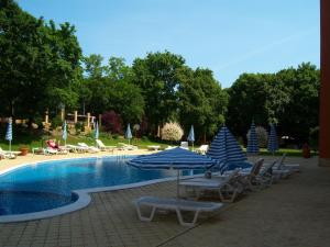 een zwembad met blauwe en witte parasols en ligstoelen bij Luxury Sunrise Complex Apartment in Goudstrand