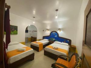 a room with three beds in a room at La Casa de Joel in Puerto Villamil