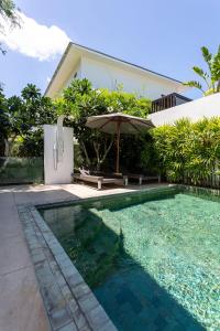 a swimming pool in front of a house with an umbrella at Вилла Vista Del Mare in Koh Samui