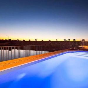 a blue swimming pool with a fence in the background at Gecko - On the Marina with Pool & Private Jetty in Exmouth