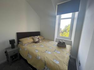 een slaapkamer met een bed met een geel dekbed en een raam bij Crown àros beag, Ultra City Central 2 bedroom apartment with free parking onsite in Inverness