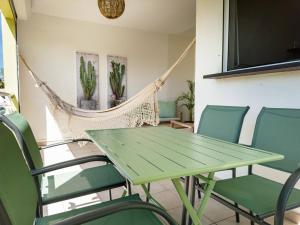 a hammock in a room with a green table and chairs at PROMO ! Cocon Dumyse, proche du Jardin botanique ! in Petit-Bourg