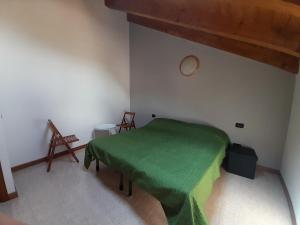 ArsieroにあるAgriturismo Val di Ferroの緑色のベッドと椅子2脚が備わる客室です。