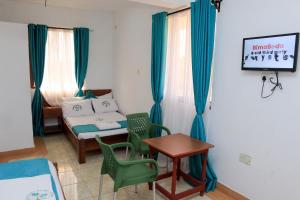 Greenyard Resort Mtwapa في متوابا: غرفة صغيرة بسرير وطاولة وكراسي