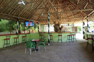 a bar with chairs and a table and a television at Greenyard Resort Mtwapa in Mtwapa
