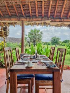 a wooden table with chairs and a tablecloth on it at Pangani Cliffs Lodge in Pangani