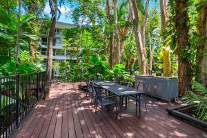 una mesa y sillas en una terraza de madera con árboles en Hotel Drift 3205 en Palm Cove