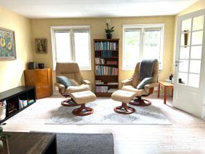 Ljunghusen Guesthouse : غرفة معيشة مع ثلاثة كراسي ورف كتاب