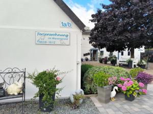 un cartello sul lato di un edificio bianco con piante di Ferienwohnung im Wiesengrund a Tarp