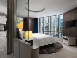 sypialnia z dużym łóżkiem i dużym oknem w obiekcie The Grove Suites by GRAND ASTON w Dżakarcie