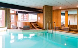 a large swimming pool with chairs and a staircase at Résidence Lagrange Vacances Le Roc Belle Face in Arc 1600