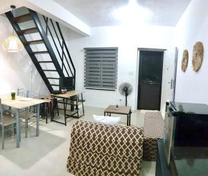 ein Wohnzimmer mit einer Treppe sowie Tischen und Stühlen in der Unterkunft Rockmelon Guest House in Mabalacat