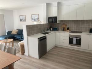 a kitchen with white cabinets and a living room at Kincaid@230 in Wagga Wagga