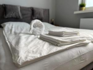 a pile of white towels sitting on top of a bed at Apartamenty Zielona in Uniejow