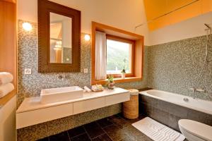 a bathroom with a sink and a tub and a mirror at Chalet Chloe - Saas-Fee in Saas-Fee