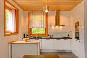 Il comprend une cuisine avec des placards blancs et un plafond en bois. dans l'établissement Chalet Chloe - Saas-Fee, à Saas-Fee