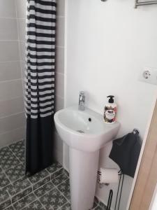 a bathroom with a white sink and a black shower curtain at Secret garden house in the center of Sigulda in Sigulda