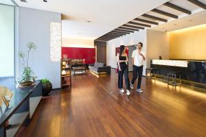 two people walking through a lobby of a building at Hotel Resol Trinity Kanazawa in Kanazawa