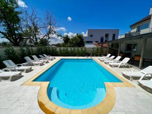 una piscina con tumbonas y sillas alrededor en XO Residence en Arad