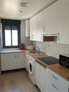 Una cocina con gabinetes blancos y lavadora. en Casco Antiguo PONDOS, en Linares