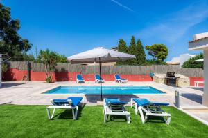 uma piscina com duas cadeiras e um guarda-sol e duas espreguiçadeiras em Villa Neptuno em Cala Ratjada