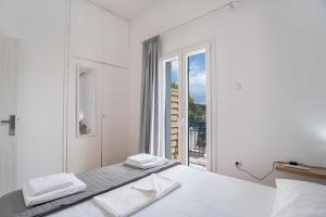 a white bedroom with a bed and a large window at Kefos Apartments Paros in Kóstos