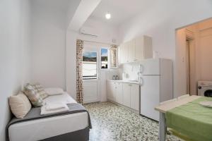 a small kitchen with a couch and a refrigerator at Kefos Apartments Paros in Kóstos