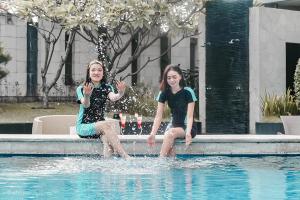 Due donne sedute in acqua in una piscina di Grand Jatra Hotel Pekanbaru a Pekanbaru