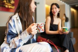 金泽金泽三神大酒店的一名男子与一名女子手捧咖啡杯