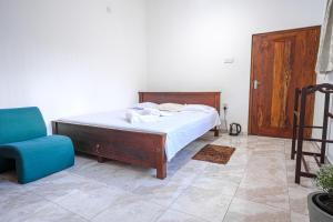 a bedroom with a bed and a blue chair at Talalla Village Beach Resort in Talalla