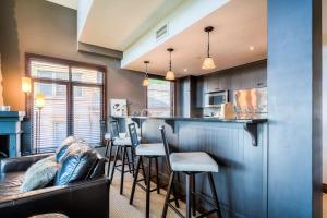 a kitchen with a bar with a couch and chairs at Luxurious Altitude Ski-in/Ski-out in Mont-Tremblant