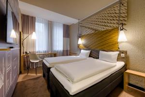 a hotel room with two beds and a table at Ibis Hotel Köln Am Dom in Cologne