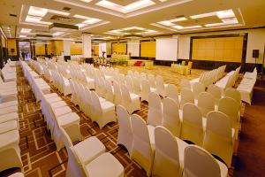 Großes Zimmer mit weißen Stühlen und einem Whiteboard. in der Unterkunft Grand Jatra Hotel Pekanbaru in Pekanbaru