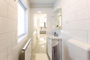 La salle de bains blanche est pourvue d'un lavabo et d'un miroir. dans l'établissement apartmani SUN & MOON, à Bjelovar