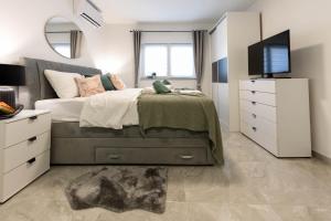 1 dormitorio con 1 cama con TV y vestidor en apartmani SUN & MOON, en Bjelovar