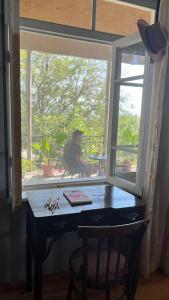 eine Person, die an einem Tisch sitzt und aus einem Fenster schaut in der Unterkunft House In The Forest in Sighnaghi