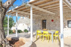 a patio with a table and chairs under a wooden pergola at TD Trulli Albapetra Pool Olive Trees in Polignano a Mare