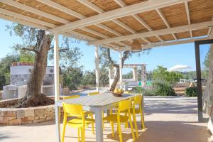 a white table and chairs under a wooden pergola at TD Trulli Albapetra Pool Olive Trees in Polignano a Mare