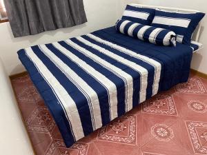 1 cama con edredón de rayas azul y blanco en ศรีวดีโฮม(Sriwadee Home), en Ban Phai