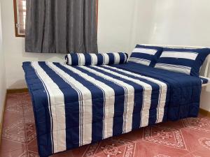 a bed with blue and white striped sheets and pillows at ศรีวดีโฮม(Sriwadee Home) in Ban Phai