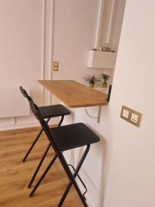 einem Holztisch und einem Stuhl neben einer Wand in der Unterkunft Très beau studio au pied du métro in Vincennes