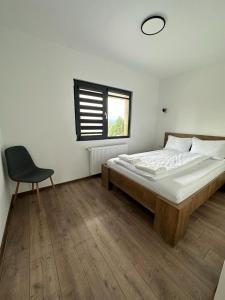 a bedroom with a bed and a chair and a window at Cabana The One in Beliş