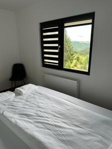 a bedroom with a large white bed with a window at Cabana The One in Beliş