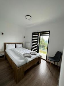 a bedroom with a bed and a chair and a window at Cabana The One in Beliş
