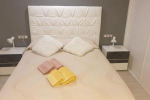 ein weißes Bett mit zwei Handtüchern und zwei Nachttischen in der Unterkunft FANTASTIC APARTMENT, NEWLY RENOVATED in Madrid