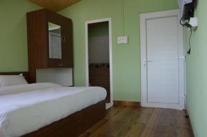 een slaapkamer met een bed en een deur met een spiegel bij Upvan Guest House and Residence in Bhīm Tāl