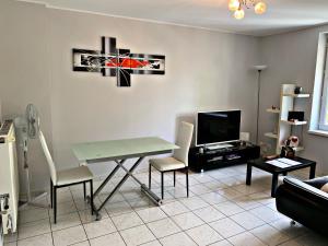 ein Wohnzimmer mit einem Tisch, Stühlen und einem TV in der Unterkunft Pôle Thermal & Touristique Amnéville in Amnéville