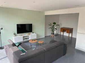 een woonkamer met een bank en een flatscreen-tv bij Maison Beau in Veurne