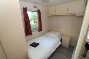 a small bed in a small room with a window at De Zuidvliet chalet 1 in Wolphaartsdijk